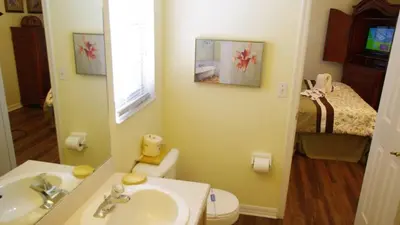 a bathroom with a sink and a toilet and a bed at Rocco's Retreat in Orlando