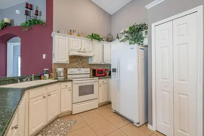 a kitchen with white cabinets and a white refrigerator at Pool Paradise in Orlando