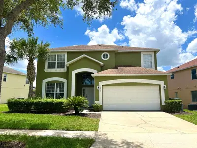 a green house with a garage in a yard at Island Paradise in Kissimmee