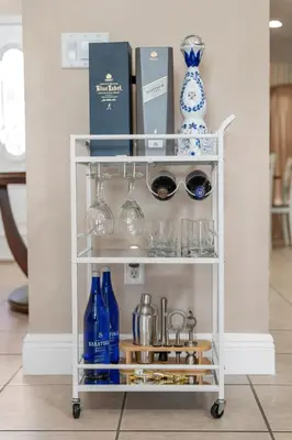 a white cart with glasses and wine bottles at Lakefront Home with Game Room and Views in Kissimmee