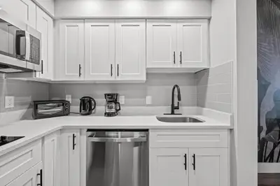 a white kitchen with white cabinets and a sink at King suite near Epic & Universal, free parking in Orlando