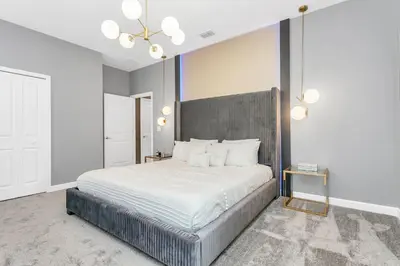 a bedroom with a large bed with white sheets at Huge 9-Bedroom Luxury Villa Near Disney With Pool in Kissimmee