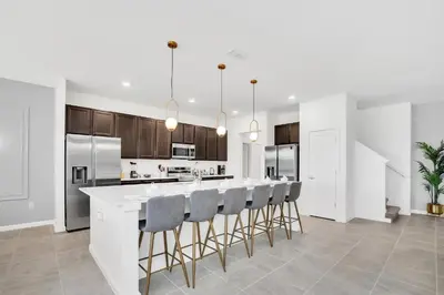 a kitchen with a large white island with bar stools at Disney-Adjacent 15Bd15Ba Oasis With Private Pool in Kissimmee