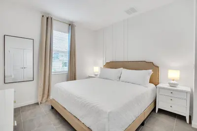 a white bedroom with a bed and a window at Disney-Adjacent 15Bd15Ba Oasis With Private Pool in Kissimmee