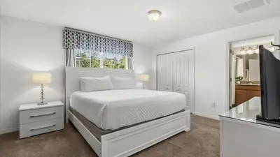 a white bedroom with a bed and a television at Family Resort Getaway w Pool & Patio near Disney in Kissimmee