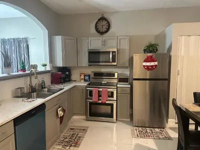 a kitchen with stainless steel appliances and a clock on the wall at Orlando Lakefront Pool Villa 25 min Disney & Univ in Orlando