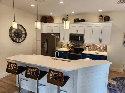 a kitchen with white cabinets and a kitchen island with chairs at Mickeys Magical Escape in Orlando