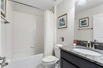 a white bathroom with a toilet and a sink at Casa 5Q c/ Piscina Sul e Game Room – Storey Lake in Kissimmee