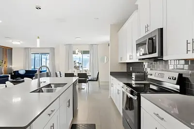 a kitchen with white cabinets and black appliances at Casa 6Q c/ Piscina & Quartos Temáticos in Kissimmee