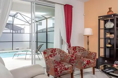 a living room with two chairs and a pool at Casa 6Q c/ Piscina – 10 Min da Disney in Kissimmee