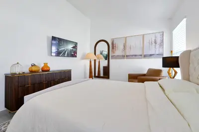 a white bedroom with a bed and a chair at Luxury Villa, Welcome to EDC, Pool & Spa in Orlando
