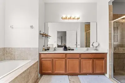 a bathroom with two sinks and a tub and a mirror at Paradise Falls Stay for 13 in Kissimmee