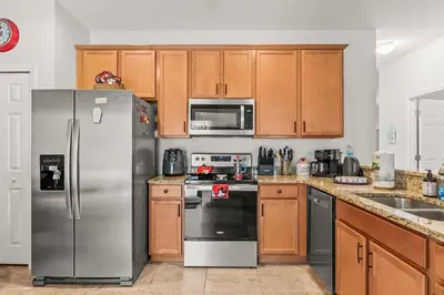 a kitchen with stainless steel appliances and wooden cabinets at Paradise Falls Stay for 13 in Kissimmee