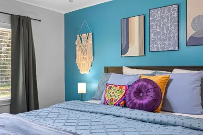 a blue bedroom with a bed with colorful pillows at Red Jordan Boho Style Vacation Home in Orlando
