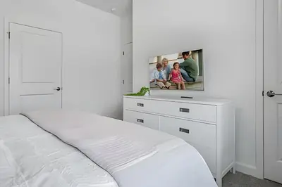 a white bedroom with a bed and a picture on the wall at Casa 4Q Storey Lake c/ Piscina e Quartos Disney in Kissimmee