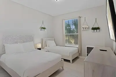 a white bedroom with a bed and a chair at Apartamento 3Q Vista Cay Perto dos Parques in Orlando