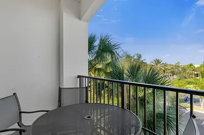 a balcony with a glass table and chairs and palm trees at Apartamento 3Q Vista Cay Perto dos Parques in Orlando
