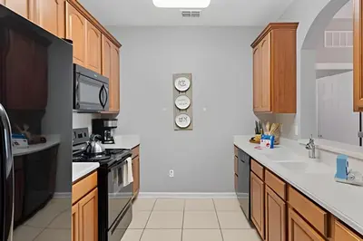 a kitchen with wooden cabinets and white counter tops at Apartamento 3Q Vista Cay Perto dos Parques in Orlando