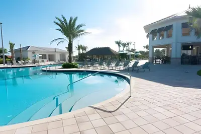 a swimming pool with chairs and a building at Villa 6Q Luxo c/ Piscina, Spa e Perto da Disney in Kissimmee
