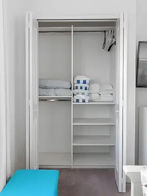 a white closet with white shelves and a blue stool at Villa 6Q Storey Lake c/ Piscina, Spa e EV Charger in Kissimmee