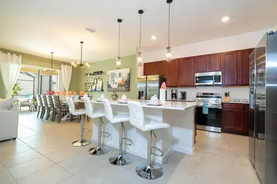 a kitchen with a large island with white bar stools at Family Friendly 12Bd w Jacuzzi Veranda Palms 4401 in Kissimmee