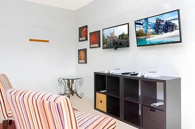 a living room with two chairs and a tv on the wall at Casa 4Q Disney c/ Piscina e Quartos Temáticos in Kissimmee