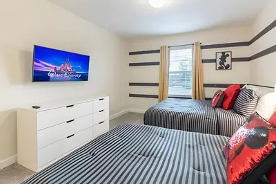 a bedroom with two beds and a tv on the wall at Casa 4Q Storey Lake c/ Piscina e Mickey in Kissimmee