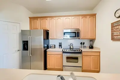 a kitchen with wooden cabinets and a stainless steel refrigerator at Apto 3Q Vista Cay Perto da Universal e OCCC in Orlando