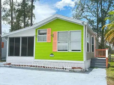 a small green and white house with a porch at Casita próximo Disney - mickeyfl-2 in Kissimmee