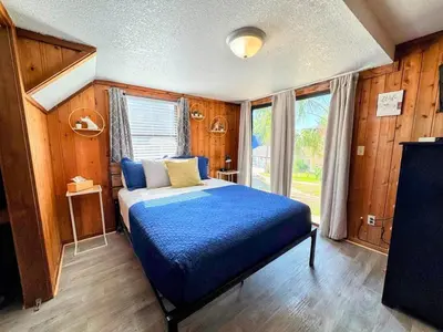 a bedroom with a blue bed in a room with wooden walls at Pumba's Place - Fun, Lake, Pool- No Cleaning Fees! in Clermont