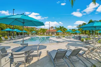 a pool with tables and chairs and blue umbrellas at LOCATION - Clubhouse & Pool in Orlando