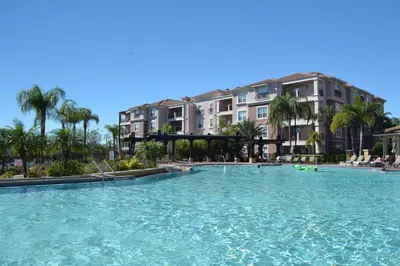 a large swimming pool with palm trees and buildings at LOCATION - Clubhouse & Pool in Orlando