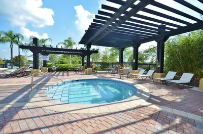 a swimming pool in a patio with chairs and an umbrella at LOCATION - Clubhouse & Pool in Orlando