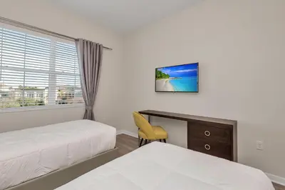 a bedroom with two beds and a desk and a window at WOW New Upscale Penthouse in Orlando