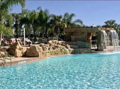 a swimming pool with a waterfall in a resort at Cheerful 5 Bdr Sunny Pool in Kissimmee