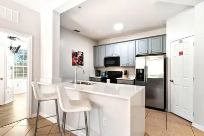 a kitchen with white cabinets and a kitchen island with stools at Vista Cay Remodeled WOW in Orlando
