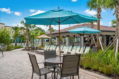 a patio with tables and chairs with blue umbrellas at Vista Cay Remodeled WOW in Orlando