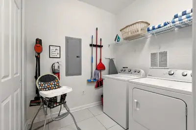 a laundry room with a washing machine and a chair at Direct Lake Front View Luxury in Orlando