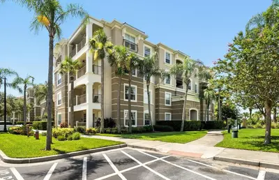 an apartment building with palm trees and a parking lot at Huge Luxury Ground Floor 103 in Orlando