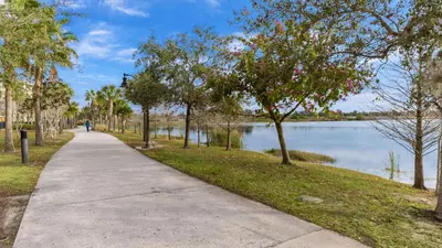 a walking path next to a lake with trees at Huge Stunning Corner Home 304 in Orlando