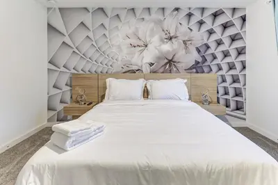 a bedroom with a large white bed with flowers on the wall at Luxury Town House Near Disney in Kissimmee