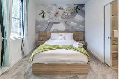 a bedroom with a large bed with a flower chandelier at Luxury Town House Near Disney in Kissimmee