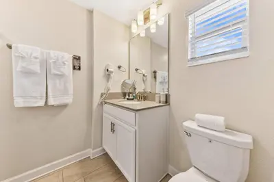 a bathroom with a toilet and a sink and a mirror at Gorgeous 5Bd w Pool & Lazy River at Storey Lake 4989 in Kissimmee