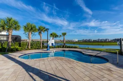 a swimming pool with palm trees and a body of water at 5 Bedrooms 4 Bathrooms Storey Lake 4984Wa in Kissimmee