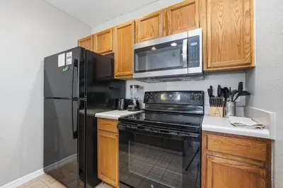 a kitchen with a black appliances and wooden cabinets at Disney 8mi Heated Resort Pool Hot Tub Fitness in Kissimmee