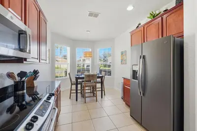 a kitchen with a refrigerator and a table with chairs at Disney Family Escape - Stunning 5-Bed Villa with Private Pool in Orlando