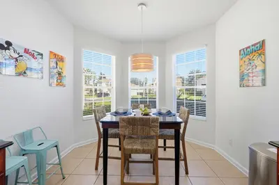 a dining room with a table and chairs and windows at Disney Family Escape - Stunning 5-Bed Villa with Private Pool in Orlando