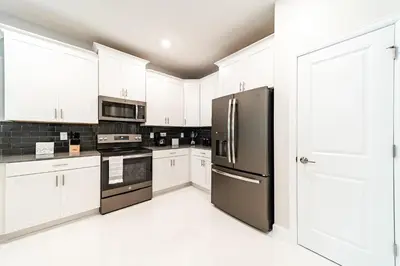 a kitchen with black appliances and white cabinets at Themed 9BR Retreat Pool & Soccer Fun in Kissimmee