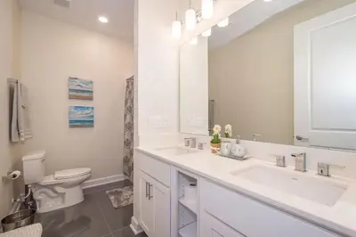 a bathroom with a sink and a toilet and a mirror at Spacious Villa w Pool Slides and Lush Nature Views in Kissimmee