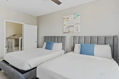 two beds in a bedroom with white and blue at Apartamento 3Q Vista Cay c/ Varanda e Jogos in Orlando
